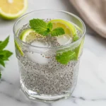 Ultra close-up top-down view of Chia Seeds and Coconut Water Electrolyte Drink in a clear glass with plump chia seeds, ice, and condensation, garnished with lemon and mint, showing refreshing natural textures.